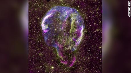 Gezeigt wird ein Radio- (lila), UV- (gelb) und Röntgenbild (blau) des Cygnus-Ring-Supernova-Überrests in der Milchstraße. 