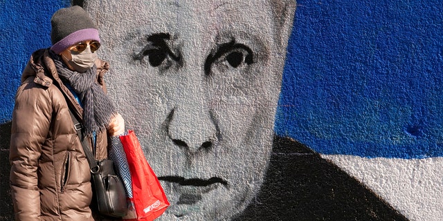 Eine Frau geht am Samstag, 12. März 2022, in Belgrad, Serbien, an einem Wandgemälde vorbei, das den russischen Präsidenten Wladimir Putin darstellt. 