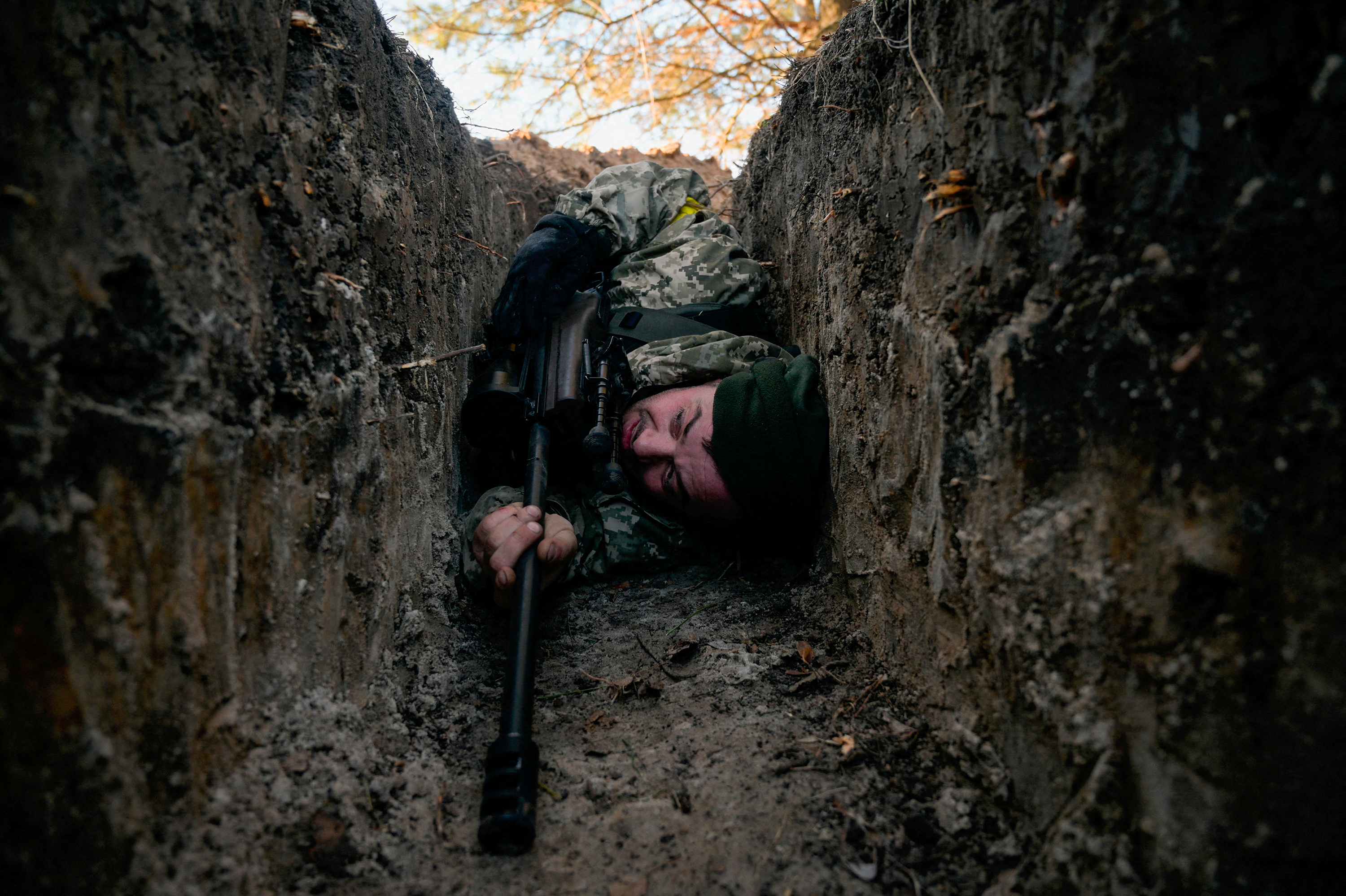 Ein ukrainischer Soldat versteckt sich am 10. März vor einem Luftangriff mit einem Hubschrauber in der Nähe von Demidjew, Ukraine. 