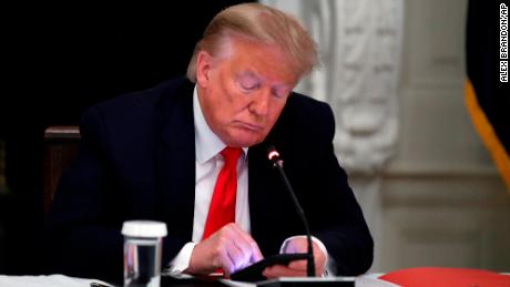 Der frühere Präsident Donald Trump schaut während eines Rundtischgesprächs mit Gouverneuren der Bundesstaaten über die Wiedereröffnung kleiner Unternehmen in Amerika im Speisesaal des Weißen Hauses in Washington am 18. Juni 2020 auf sein Telefon. 