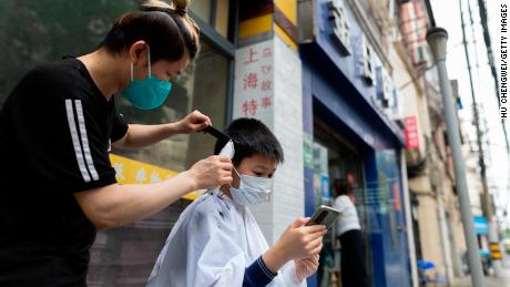 Ein Friseur schneidet am Mittwoch auf einer Straße in Shanghai einem Jungen die Haare.